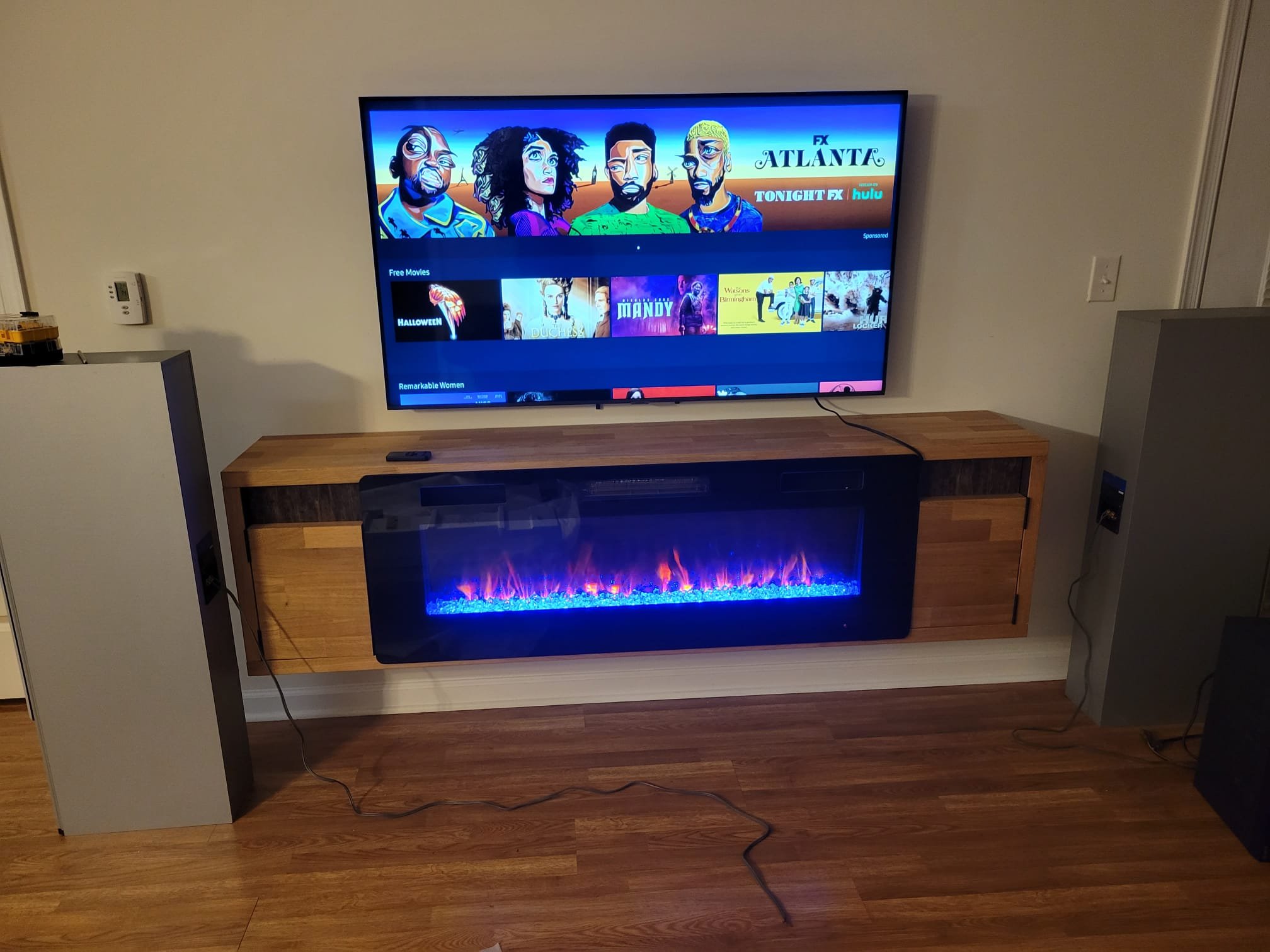 Large TV mounted above a floating console with hidden wires in a Queens home. Clean TV mounting and wire concealment services.